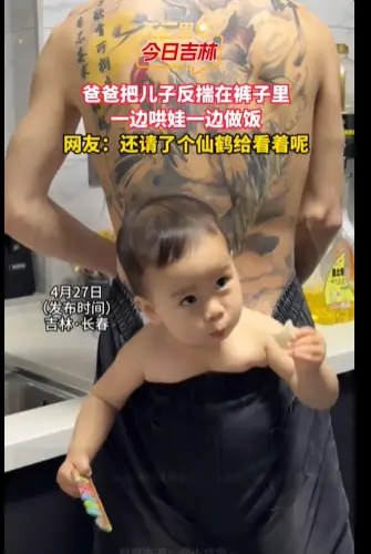 爸爸带娃将儿子揣在后裤腰里，做饭哄娃两不误。